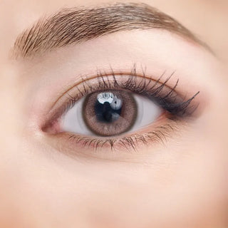 Close-up of eye with long lashes wearing EyeCandys NEOism Milk Brown prescription colored contact lens - warm natural brown color, detailed lens design, comfortable daily wear, trendy cosmetic lenses
