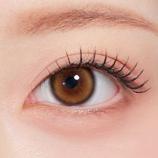 Olala Glee Brown color contact lens on top of a dark eye paired with subtle peach eyeshadow and curled wispy eyelashes