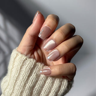 Hand wearing EyeCandys Soft Spoken press on nails featuring nude ballet pink cat eye base with chrome French tips and subtle diamante accent.