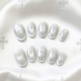 Cygnus press on nails by EyeCandys featuring ice grey cat eye base with silver metallic cross motifs and etched lines in a short almond shape luxury reusable nail set.