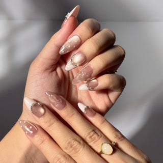 Hand showcasing EyeCandys Ballet Slippers press on nails with satin-like nude pink tone, pearl accents, and delicate French tips.