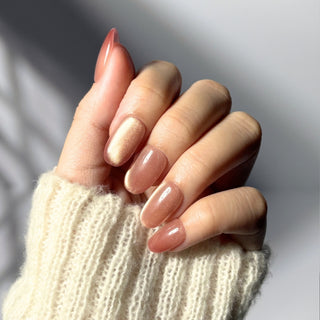 Hand showcasing EyeCandys Grapefruit Soda press on nails featuring translucent base and soft pink cat-eye gradient.