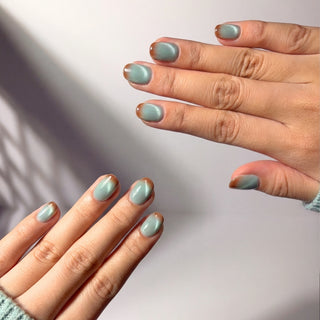 Hands showcasing EyeCandys Blue Hour Latte press on nails featuring cool blue cat-eye shimmer and warm brown tip gradient.