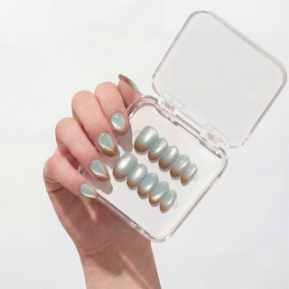 Hand wearing EyeCandys Blue Hour Latte press on nails with milky blue glassy base, soft cat-eye glow, and subtle brown gradient tips.