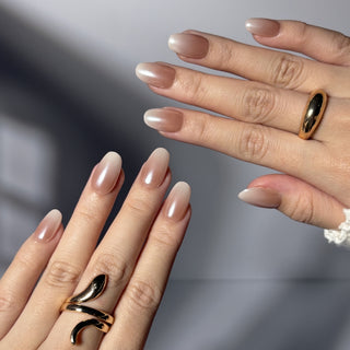 Hands wearing EyeCandys Cloud Nine press on nails with milky white baby boomer gradient and soft cat-eye shimmer with magnetic glow.