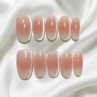 Close-up of EyeCandys Cloud Nine press on nails on a white background featuring milky white baby boomer gradient with soft cat-eye shimmer and magnetic glow.