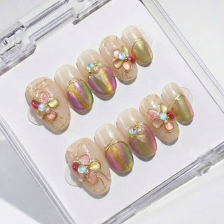 EyeCandys Miraflores press on nails featuring color shifting aurora chrome nails, champagne jelly base, delicate gold floral accents, and pastel 3D flower.