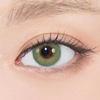 A close-up of a human eye wearing N's Collection Saba Teishoku Green (10pk) contacts from N's Collection, surrounded by natural makeup and defined eyelashes.