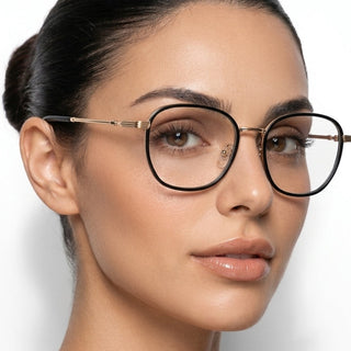 A woman with clear skin and dark hair tied back wears EyeCandys Therese Oversized Square glasses, gazing slightly to the side against a plain white background.
