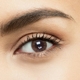 EyeCandys Truffle Brown color contacts for astigmatism shown on a model's eye (naturally dark brown), with matching simple makeup.
