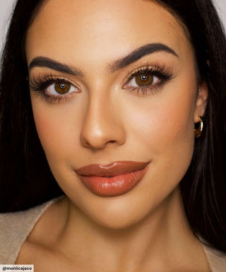 A female model with natural dark eyes wearing Pink Label Vintage brown contact lenses, complemented by subtle eyeshadow and peach lip gloss and Close-up image showcases the model's eyes