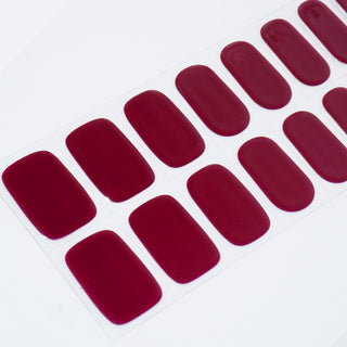 Angled image of semi-cured gel nail stickers in the design 'Wine Not?,' showcasing a rich wine-red hue with a smooth, glossy finish for an elegant and bold manicure.