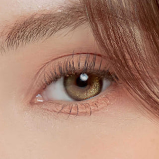 Close-up of model's eye with Winkly Green contact lens and peach eyeshadow 