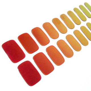 Angled image of semi-cured gel nail stickers in the design 'Apple Pie,' featuring a gradient of warm colors ranging from deep red to golden yellow, perfect for a stylish manicure.