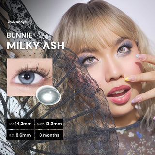 Full face of model wearing EyeCandys Milky Ash Grey colored contact lenses. Close-up highlighting silvery ash and creamy beige iris, long lashes, and soft limbal ring for a subtle, luminous eye enhancement.