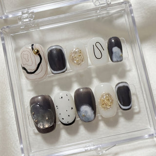 EyeCandys Concrete Poetry press on nails with minimalist cream nails, charcoal ink wash textures, and sculpted gold details in an editorial nail art style.