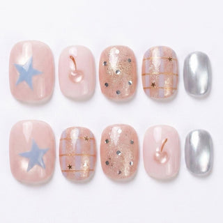 Close-up of Eyecandys Charmed, I'm Sure reusable press-on nails showcasing blue star nail art, gold cherry charm, glitter details, plaid design, and silver chrome accents.
