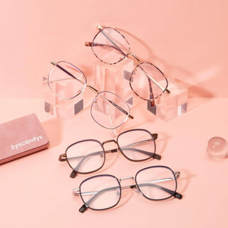 Four pairs of EyeCandys fashion glasses, including the Stunner Square frame, are arranged on clear acrylic blocks and a pink surface with a matching EyeCandys case and glass sphere, all set against a pink background.