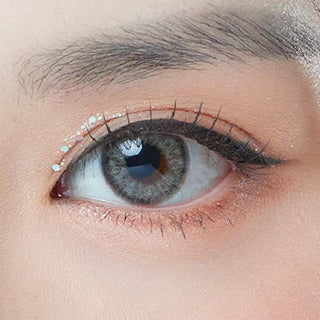Macro photograph of a dark brown eye with clean makeup showcasing the Sephia Grey prescription color contact lens, highlighting the multicolored detail and natural effect