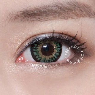 Eye adorned with Bambi Green contact lens and complementary makeup