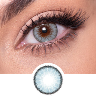 Close-up shot of a model eye wearing Desire Glacier Blue colored contact lens in one eye that is naturally dark-brown with natural rosegold eye make up