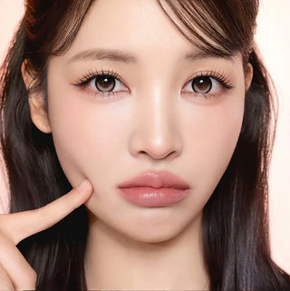 Model with natural makeup and long lashes wearing EyeCandys i-Sha Dekame Kiss Me Milky Choco brown colored contact lenses