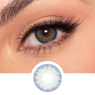 Blue multi-tone contact lens (EyeCandys Isla Blue Grotto) worn on a brown eye with neutral eye makeup and wispy eyelashes, above the eye contact design on a white background.