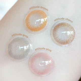 Various Attitude color contact lenses in brown, grey, chocolate and pink photographed on a wrist
