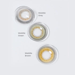 Three EyeCandys Limited Edition Maddie Series colored contacts—Grey, Green, and Brown—are shown on a white background. Each lens features a subtle, natural-looking design for bigger eyes.