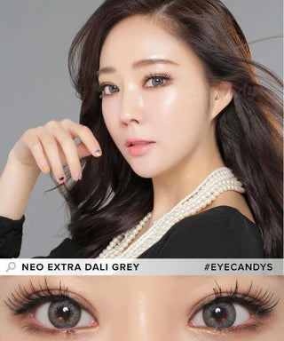 A woman with long dark hair and a pearl necklace poses, highlighting her striking grey circle lenses—NEO Vision Extra Dali Grey by NEO Vision. Text reads "NEO EXTRA DALI GREY #EYECANDYS.