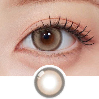 Olala Glint Brown color contact lens on top of a dark eye paired with subtle peach eyeshadow and curled wispy eyelashes, above the contact lens design.