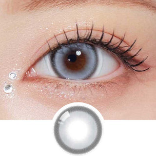 Olala Glint Grey color contact lens on top of a dark eye paired with subtle peach eyeshadow and curled wispy eyelashes, above the contact lens design.