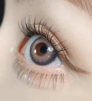 Macro shot of an eye wearing the Olola Torrid Love Beige (KR) prescription colour contact lens, showing the multi-colored detail and natural effect on dark brown eyes.