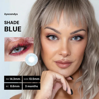A woman with wavy blonde hair and glowing makeup shows a natural look wearing EyeCandys Shade Blue high-coverage contacts. An inset close-up displays the blue lens on an eye along with product details and duration.