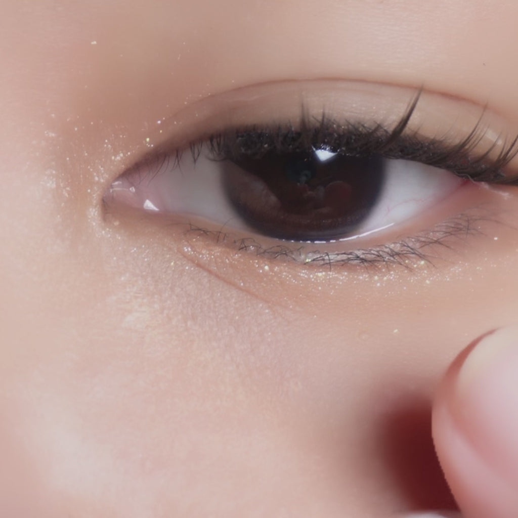 Eyecandys Libre Green contact lens sliding onto an eyeball with a dark iris of an Asian model