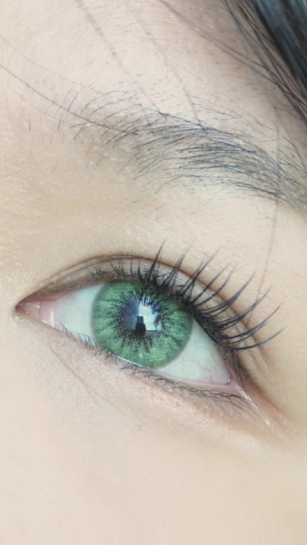 Desire Green colour contact lens for astigmatism worn on a naturally dark iris with natural eyelashes and makeup.
