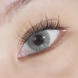 Close-up of a model wearing EyeCandys Glossy Ivory 2.0 prescription colored contact lenses with long black glue-free false lashes and soft eyeshadow, creating a luminous eye look with enhanced definition.