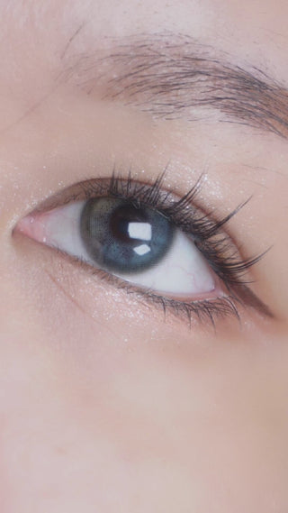 Putting on various color contact lenses for everyday wear and cosplay onto a female eye embellished with long anime-inspired eyelashes and simple makeup