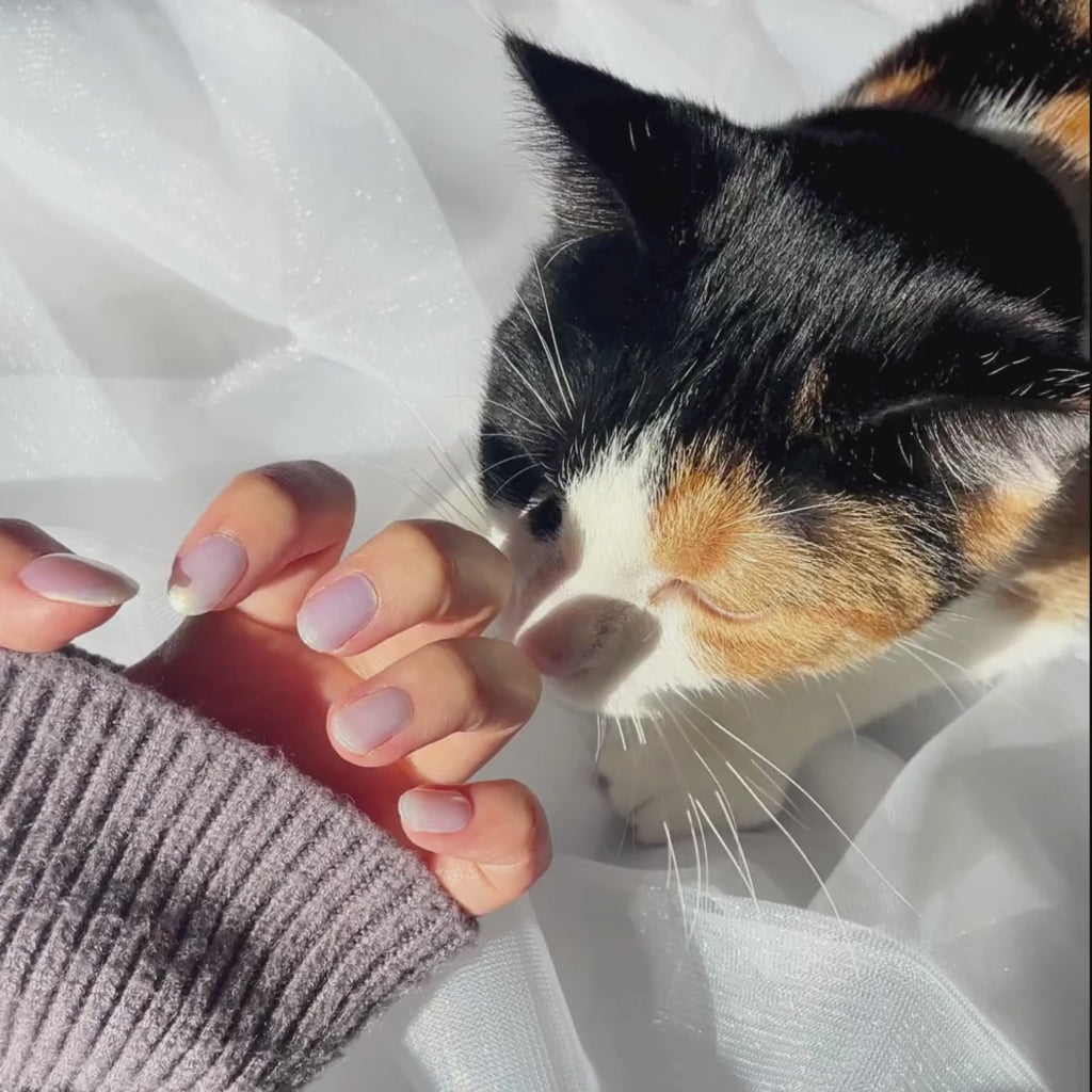 Model's hand showcasing EyeCandys Fiji Girlie Gel Nail Stickers. These iridescent white stickers offer a shimmering, elegant finish, providing a glossy, long-lasting manicure with minimal effort. The soft, radiant hue adds a touch of sophistication and style to any look.