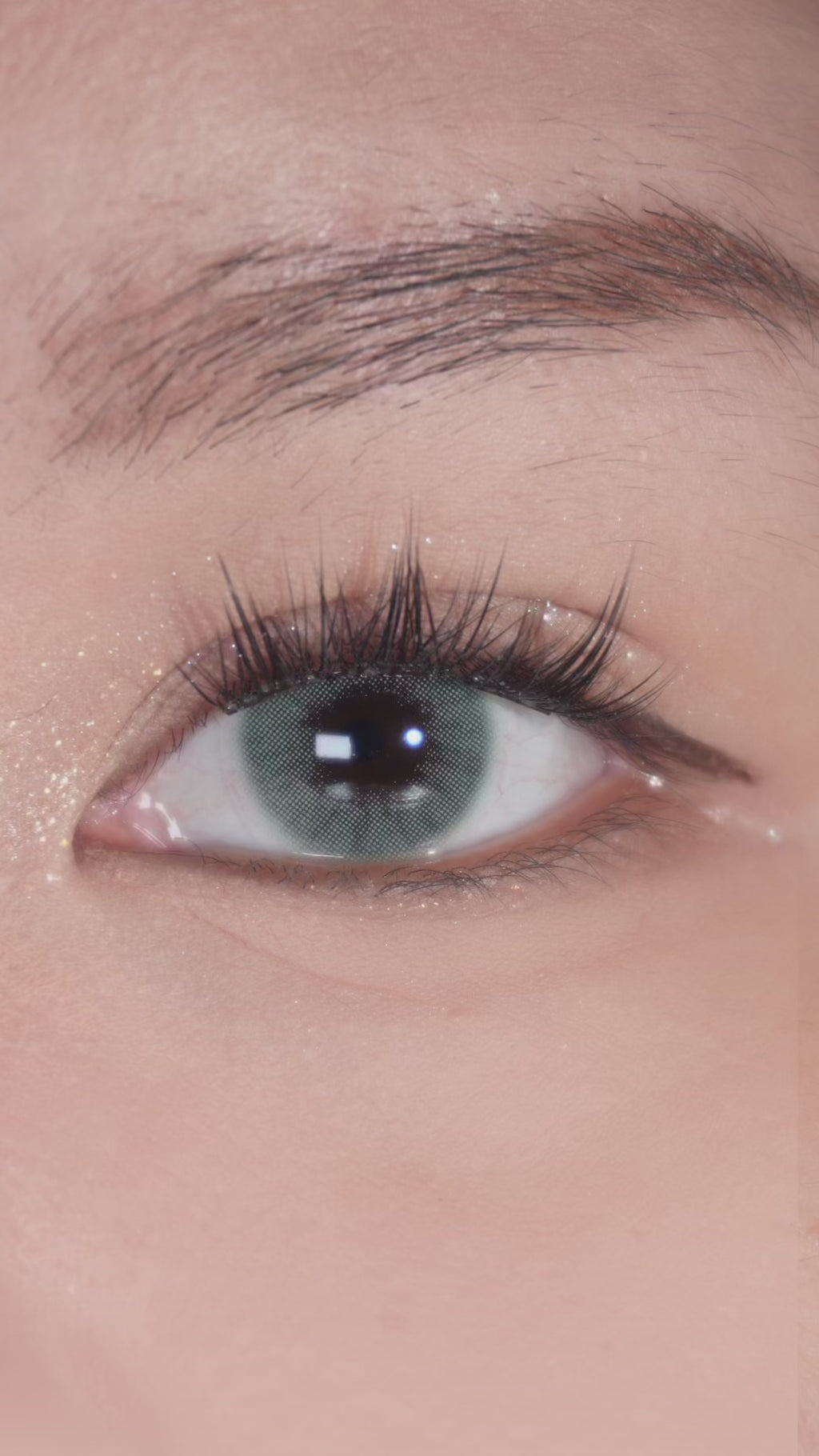 Eyes with long lashes wearing EyeCandys Glossy Green prescription colored contact lenses, blinking naturally