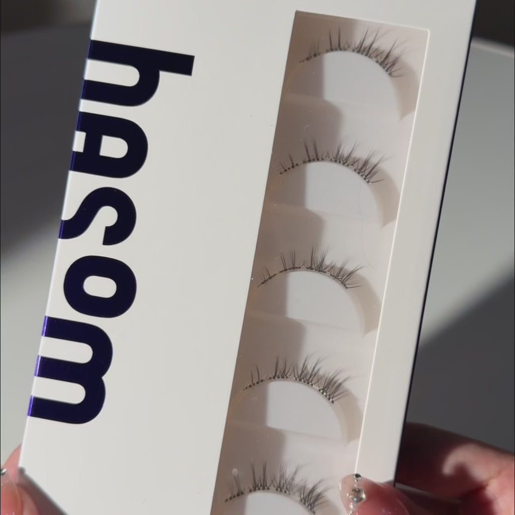 Unboxing video of EyeCandys Hasom First Touch Fancy 03 pre-glued strip lashes, showcasing the lash packaging and wispy, tapered design with a soft foxy lift at the outer corners.