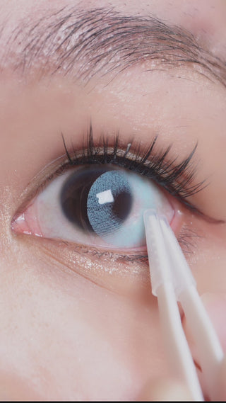 EyeCabdys Dare to be Blue contact lens sliding onto an eyeball with a dark iris of an Asian model