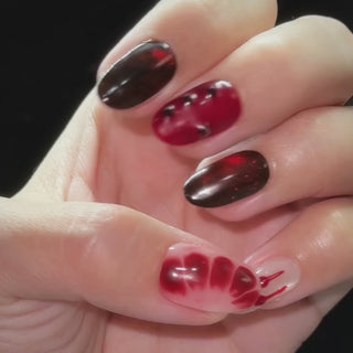 EyeCandys Blood Wedding Press-On Nails featuring short oval gothic nails with red and black cat-eye shimmer, blood drips, studs, and cross details
