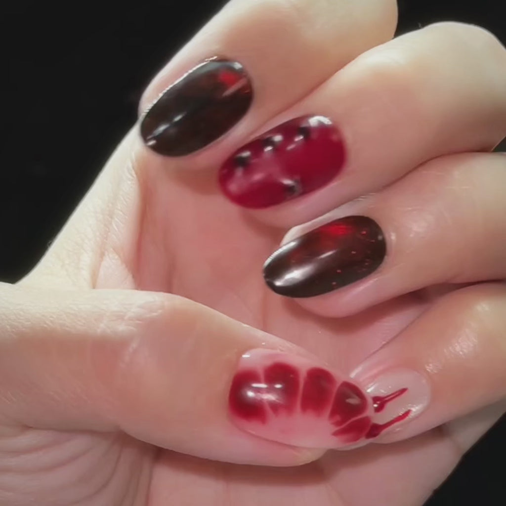 EyeCandys Blood Wedding Press-On Nails featuring short oval gothic nails with red and black cat-eye shimmer, blood drips, studs, and cross details