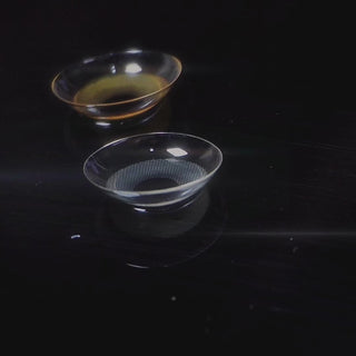 a short clips of videos showing the amelie contact lenses detail in a black background and lenses being worn by model with dark brown eyes adding na natural light up to the eye. The last clip is the amelie via rotating on top of a black platform. 