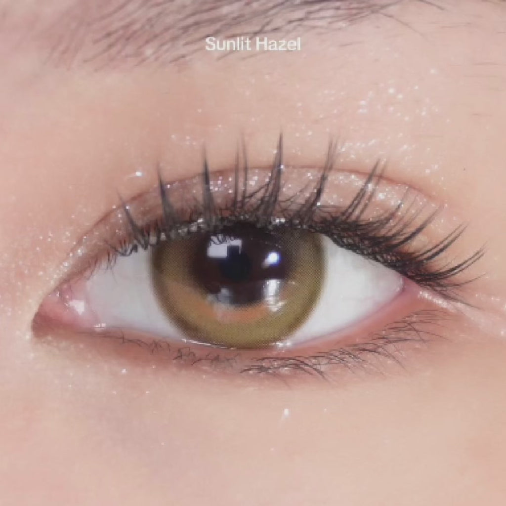 Close-up video of an eye with long lashes and glitter eye makeup wearing EyeCandys Sunlit Hazel prescription colored contact lens, showcasing warm hazel tones.