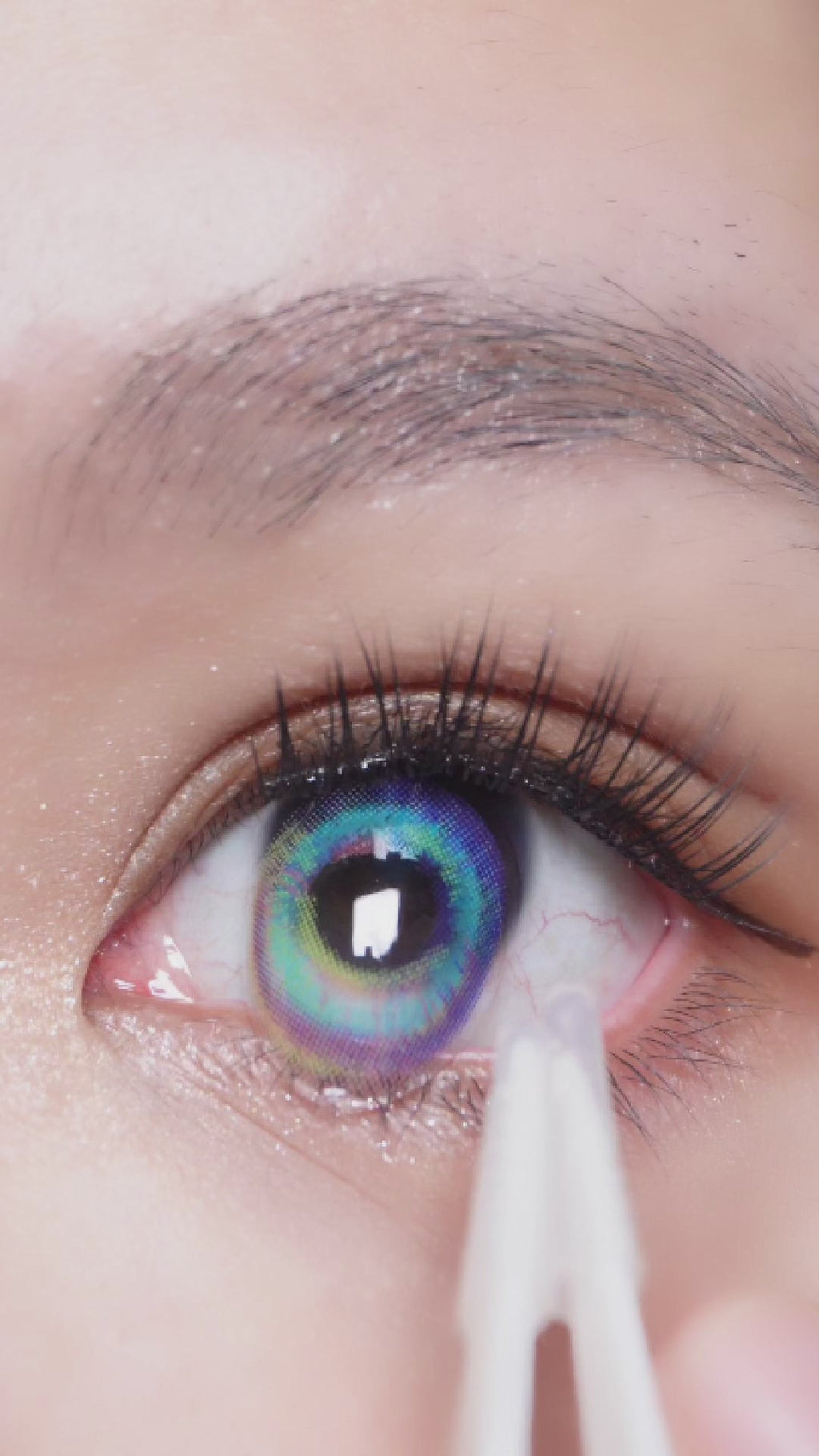 Dark eyed model wearing EyeCandys Pink Label Prism Blue colored contact lens