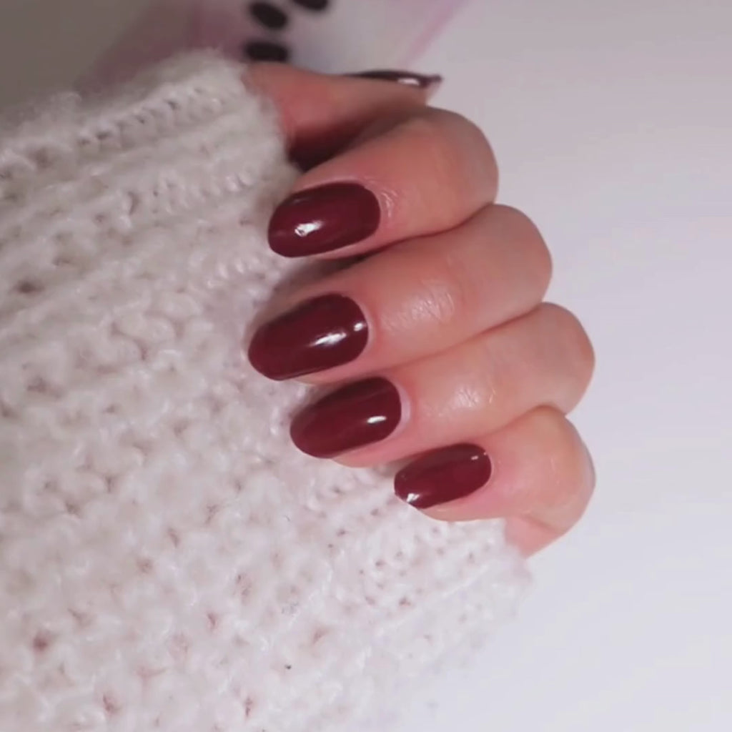 Model's hand showcasing EyeCandys Wine Not Gel Nail Stickers with a rich wine-colored design. These easy-to-apply, long-lasting gel stickers offer a chic, chip-free finish, perfect for a stylish, effortless manicure