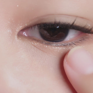 Eyecandys Libre Brown contact lens sliding onto an eyeball with a dark iris of an Asian model