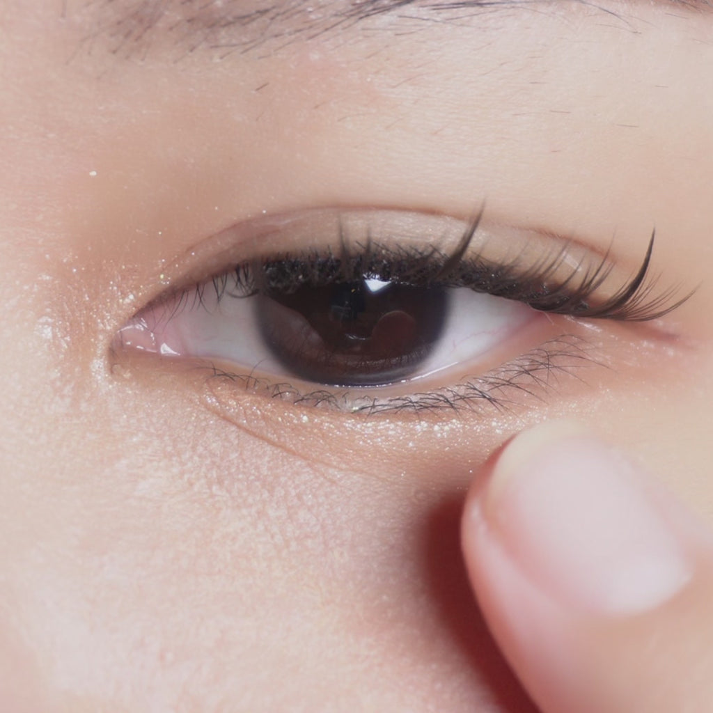 Eyecandys Libre Beige contact lens sliding onto an eyeball with a dark iris of an Asian model